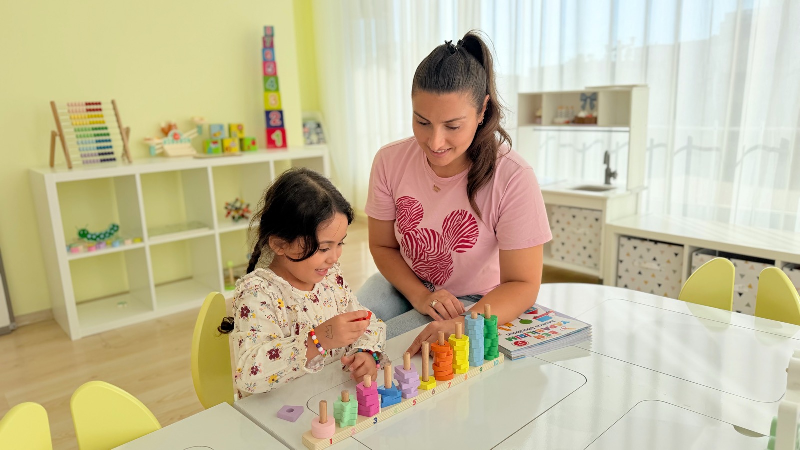 Öğretmen ve çocuk renkli sayma materyaliyle çalışıyor